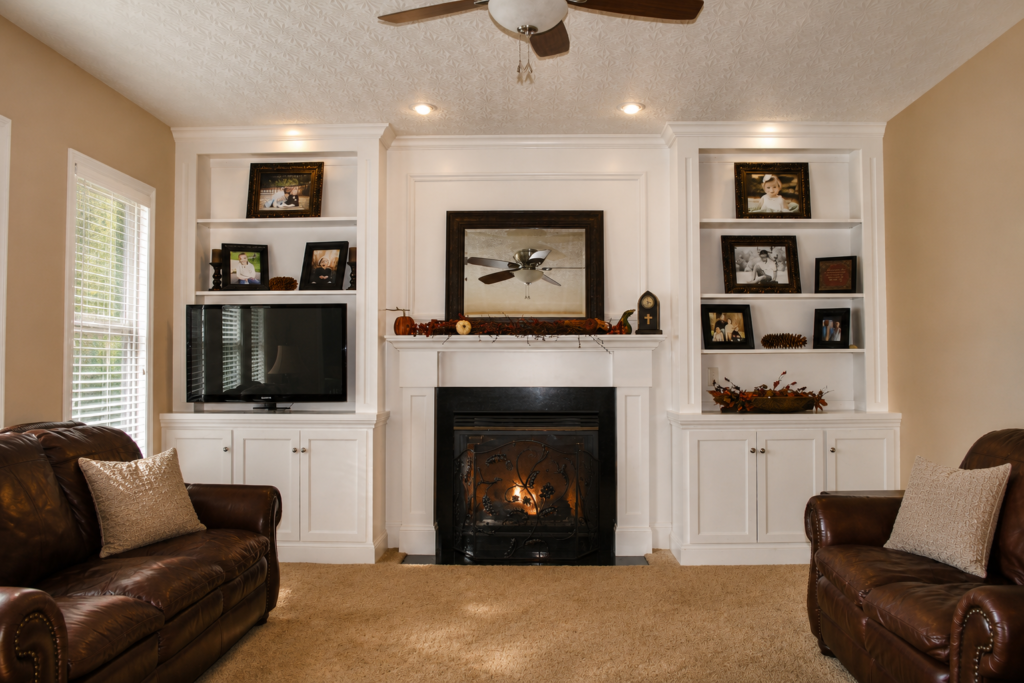 Custom white living room built-ins flanking a fireplace with integrated shelving and cabinets